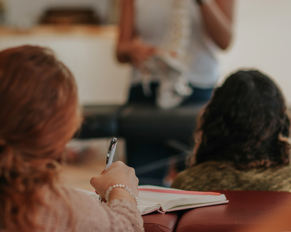 A woman takes notes while participating in a seminar with Dr. Lauren.